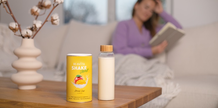 Shake BEAVITA su un tavolo con una donna sullo sfondo.